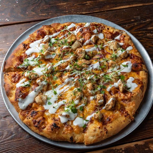 Buffalo chicken pizza from Press Box Sports Grill, topped with ranch, cheese, and microgreens.